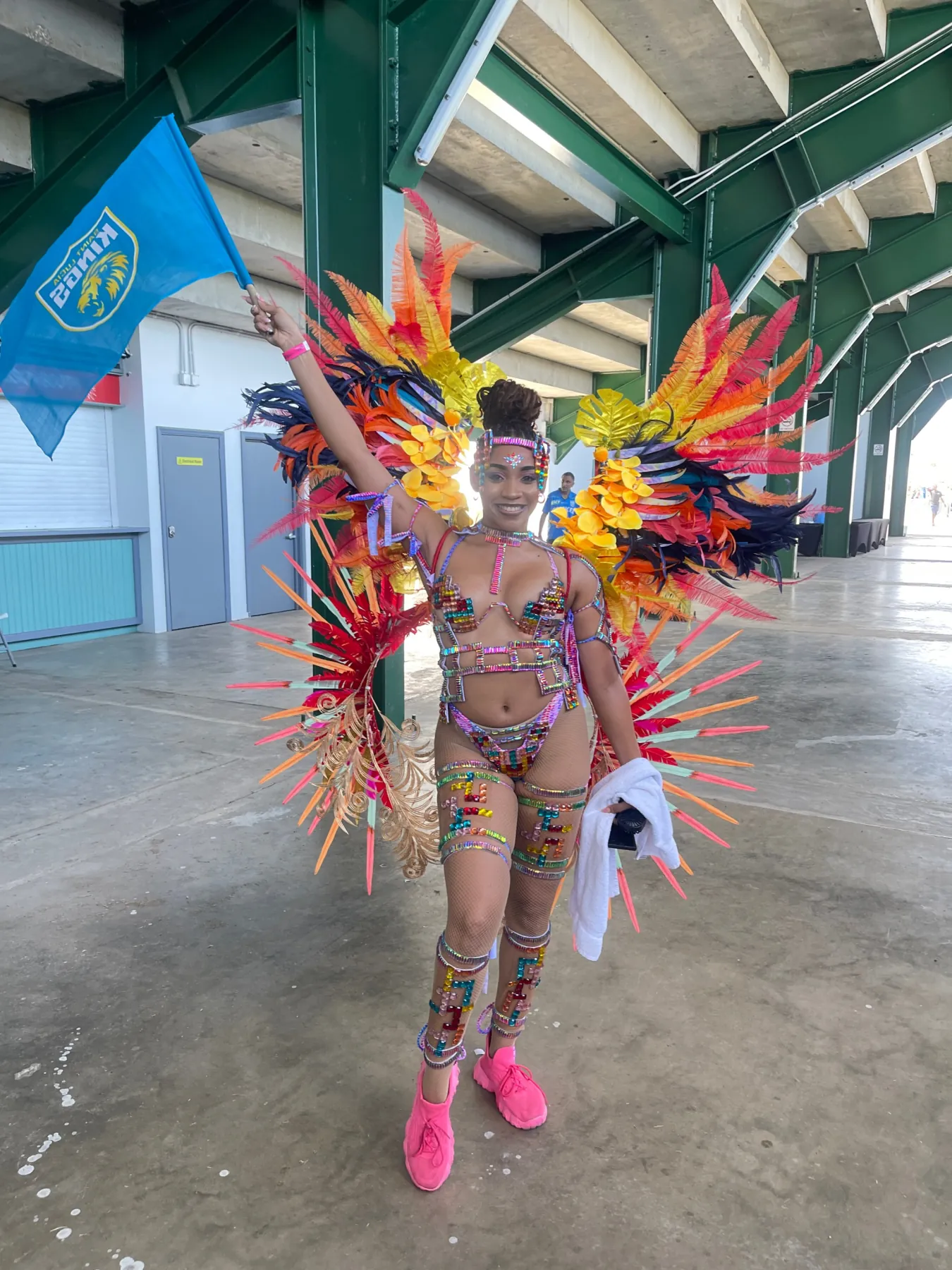Caribbean carnival dancer in feathered costume with flag